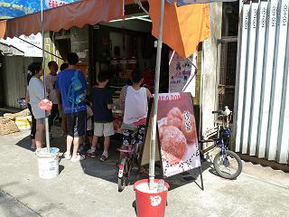 「Tai O Donus　沙翁」の看板にボール型の揚げ菓子の写真。店の前には10人ほどの人だかり